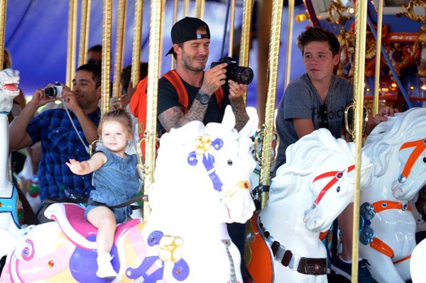 David Beckham rides the carousel at DisneyLand with daughter Harper and eldest son Brooklyn.